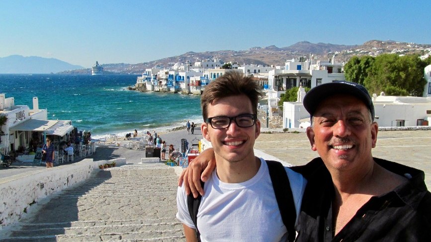 Mike with his arm around his son Jon above the whitewashed waterfront of Mykonos